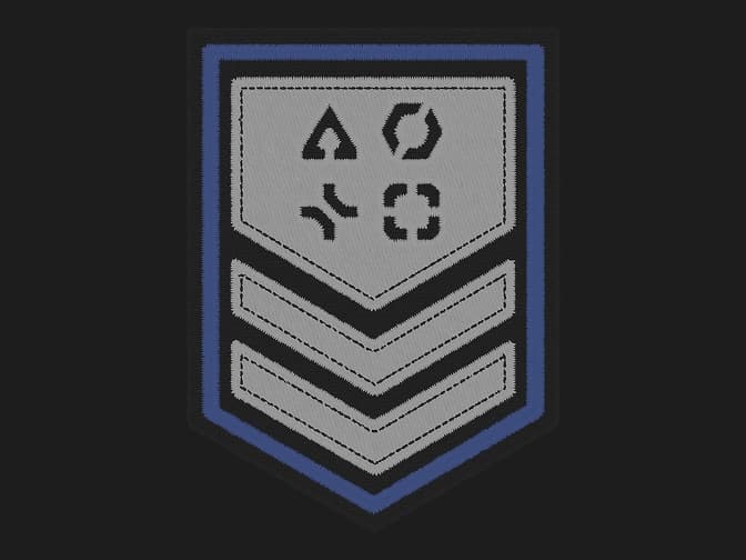 Embroidered gray badge with four symbols and stacked chevrons, outlined in blue.