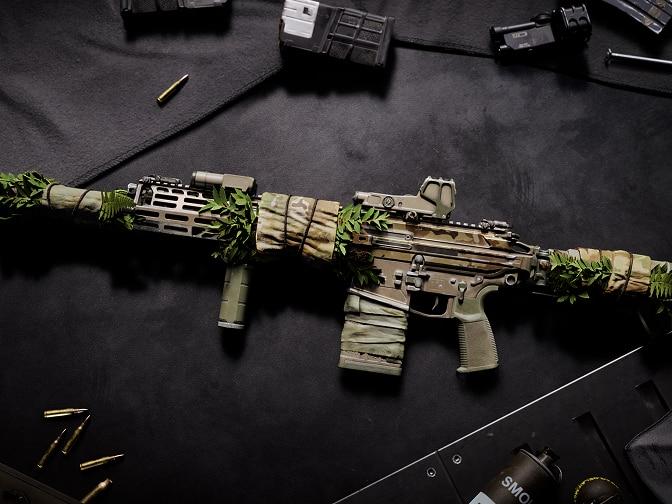 A tan, long-range rifle with leafy details.