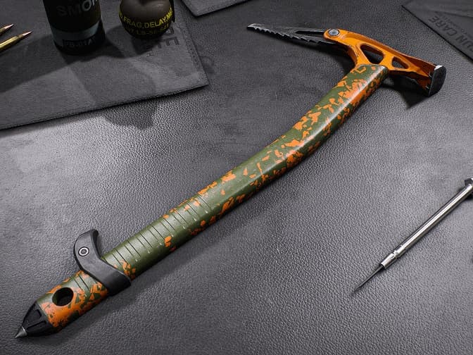Green-and-orange tactical ice climbing axe with a serrated edge and spike.