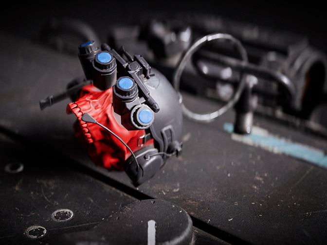 A weapon charm featuring a night vision helmet attached to a red skull.
