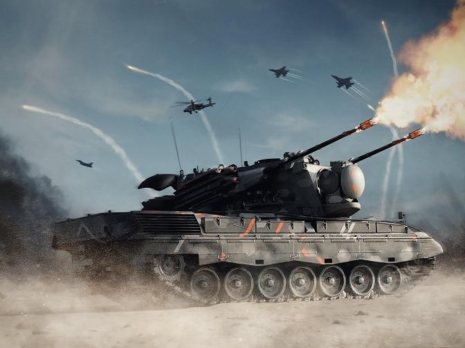 Na pierwszym planie czołg prowadzący ostrzał, nad nim przelatują samoloty.